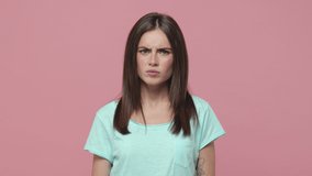 Dissatisfied young brunette woman 20s years old in casual blue t-shirt posing isolated on pink background studio. People lifestyle concept. Looking camera say no with finger gesture showing thumb down
