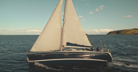 Closeup yacht sailing on open sea aerial. Nobody nature seascape with sail boat cruising at ocean bay. Mountain landscape of Arran Island, Scotland, Europe. Cinematic bright sun shine summer vacation