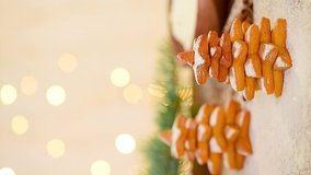 Christmas gingerbread in the shape of a Christmas tree and a star is sprinkled with powdered sugar against the light of bokeh garlands. soft focus on the carrot. vertical video