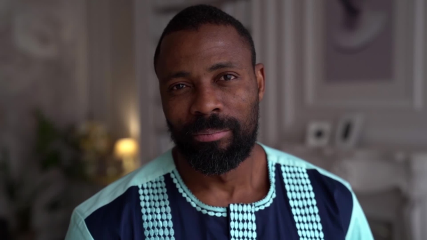 Close-up portrait of an African-American man at home in a bright office. A confident student guy wears a casual t-shirt.