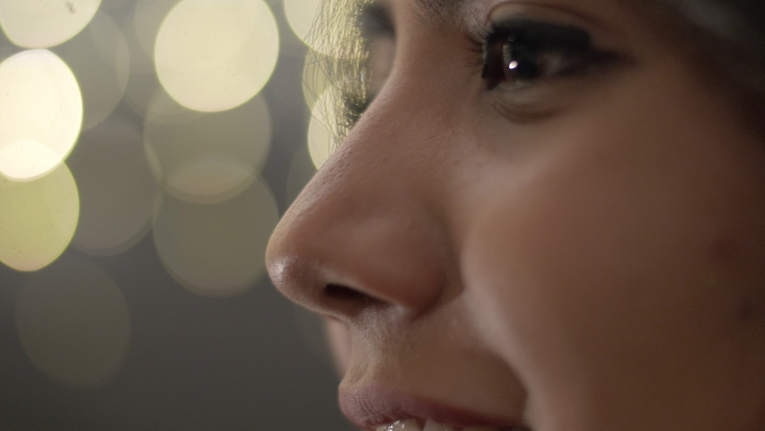 Attractive woman looking at evening lights. Extreme close-up of eyes of a surprised young female on bokeh background.