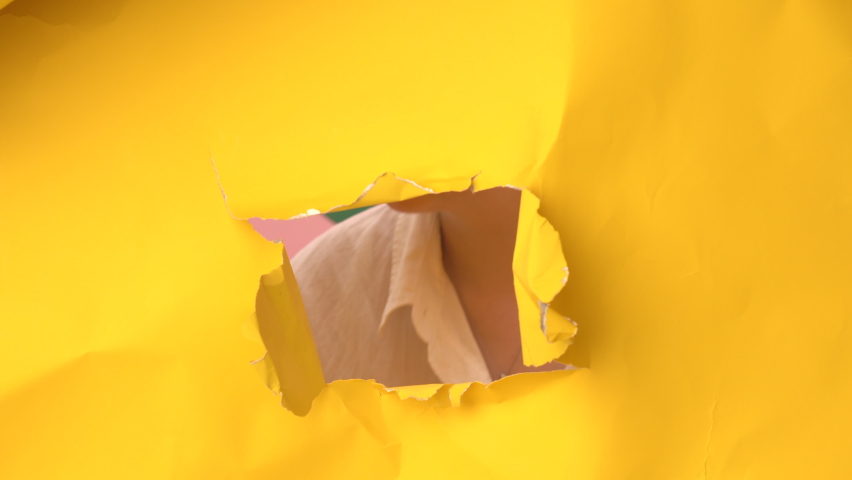 Young woman appears smiling and disappearing in a hole in big sheet of cramped yellow paper. She has short dyed blond hair and stars eye makeup.