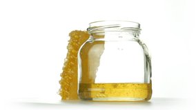 honeycomb with honey jar which is filled with honey falling from above, on white background