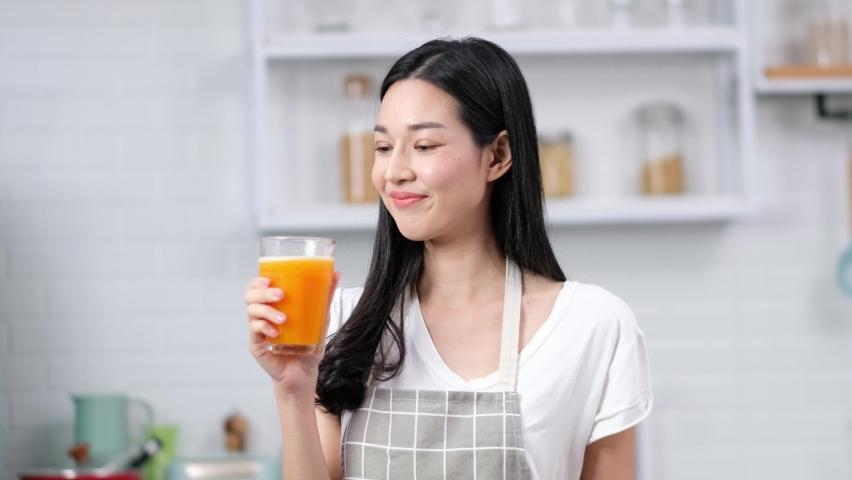 Asian woman drinking orange juice. Healthy living lifestyle.