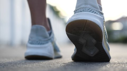 Woman running in beautiful sunrise, motion blur of woman exercising outdoors. Close up and selective focus running shoes.