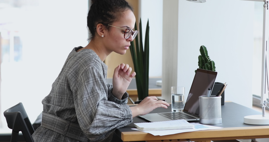 Side view concentrated african american female secretary in eyeglasses working in modern office, analyzing internet information on computer, writing notes, planning online marketing strategy. Royalty-Free Stock Footage #1061988916