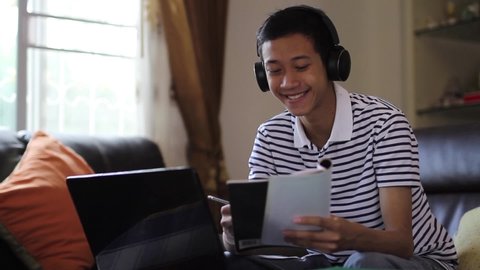 Teenager of asian boy studying on laptop and having fun with private online tutor at home. online class, education at home comcept.