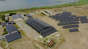 Aerial view of solar power farm mounted on roofs of rural buildings for green electrical fuel production on beautiful sunny day. Drone shoots video of energy saving
