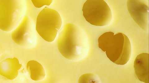 Piece of Dutch yellow cheese with holes close up full frame