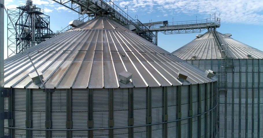 Large silver granary. Modern grain elevators. Metal industrial silos for agribusiness. New plant for storing crop. Close-up. Drone view. Royalty-Free Stock Footage #1061993995