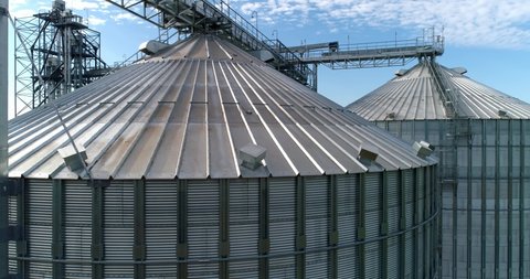 Large silver granary. Modern grain elevators. Metal industrial silos for agribusiness. New plant for storing crop. Close-up. Drone view.
