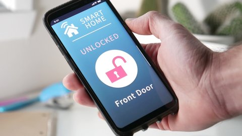 Locking the door of a house on a smartphone smart home app. Pressing the lock icon to activate the locking process.