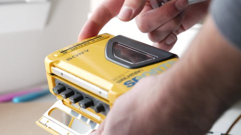 Inserting an audio cassette into a Sony Walkman portable player. Retro concept of listening to music. MONTREAL CANADA NOVEMBER 2020