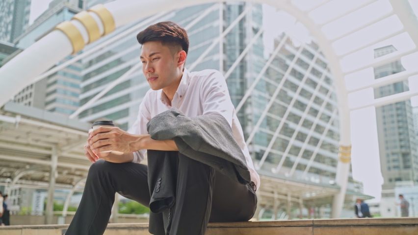Asian business man feeling sad after unemployment from his company. The man sitting outdoor    feeling stress worry about losing the job due to world economic problem from covid crisis concept. | Shutterstock HD Video #1061994667