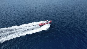 Aerial drone tracking video of red pilot boat cruising in high speed in Mediterranean deep blue sea offering navigational aid to ships