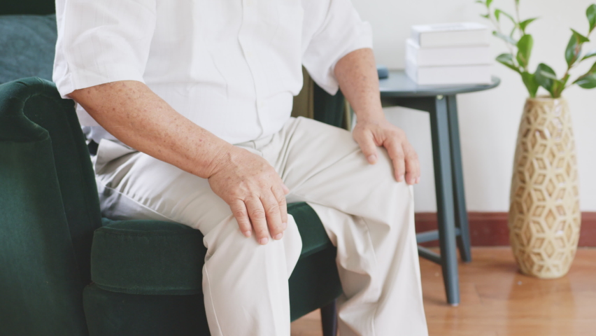 Closeup old Asian senior man feel pain, ache, hurt at knee while standing and sitting at home, osteoarthritis concept Royalty-Free Stock Footage #1061995786