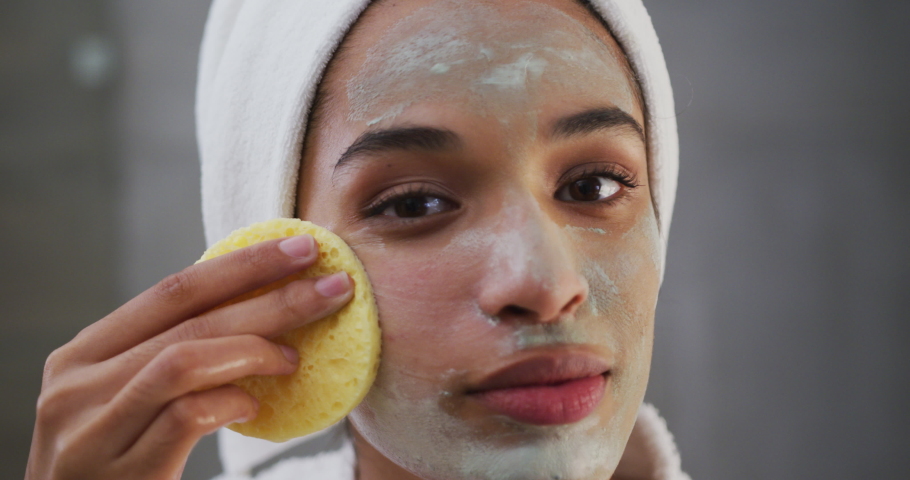 Close up of mixed race woman applying face mask in bathroom. enjoying quality time at home during coronavirus covid 19 lockdown. | Shutterstock HD Video #1061999554