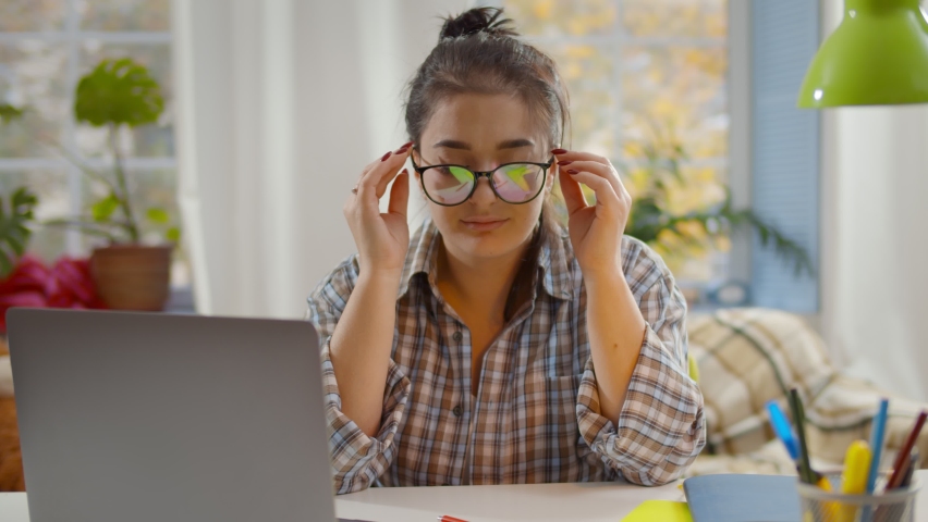 Tired mother with stress working on laptop at home with noisy children on background. Young exhausted woman putting off glasses and holding head sitting at desk with kids playing on background Royalty-Free Stock Footage #1062002062