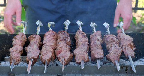 Kebab cooking outdoors on metal skewer. Traditional eastern dish - Marinated barbecue meat cooked at barbeque. Grilled pork, meat lamb, shish kebabs, shashlik - Street food popular in Europe, Russia