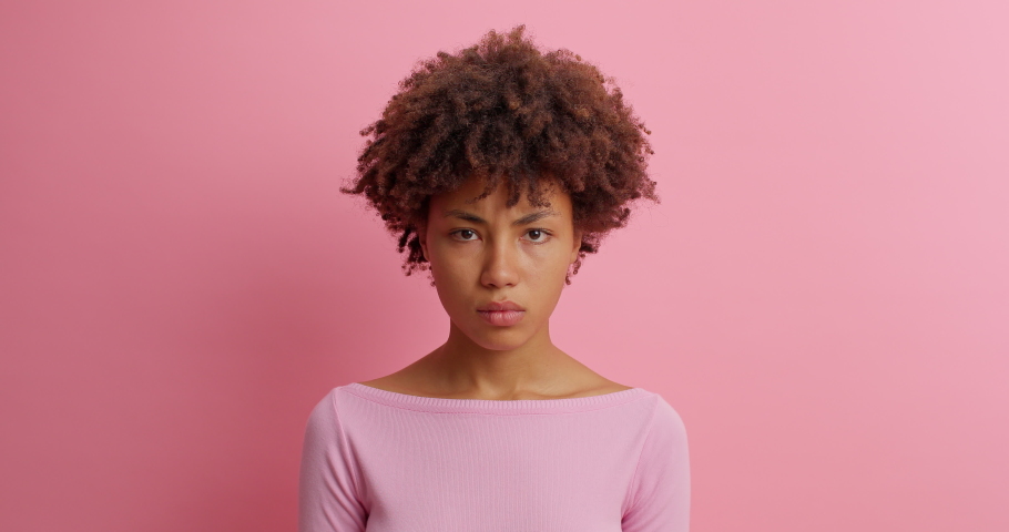 Serious young woman shakes finger and says no I dont need drressed in casual clothing poses against pink background doesnt like plan scods for bad choice prohibits action isolated on pink wall | Shutterstock HD Video #1062004837