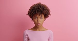 Serious young woman shakes finger and says no I dont need drressed in casual clothing poses against pink background doesnt like plan scods for bad choice prohibits action isolated on pink wall