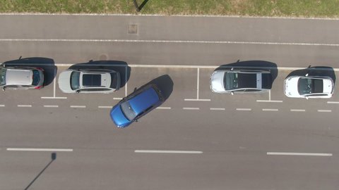 AERIAL, TOP DOWN: Flying above an autonomous car successfully parallel parking into a vacant spot at the side of a road. High-tech self-steering vehicle parks itself into empty roadside parking spot.