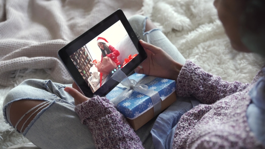 African american kid girl talking to virtual friend indian child opening Christmas gifts during online meeting on New Year holiday by video conference call chat using tablet computer sitting on bed. | Shutterstock HD Video #1062010279