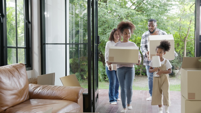 Candid african american family, parents and little girl holding carton box walk into new house move in day,relocate in existing second hand home. Loan mortgage finance in real estate property concept. Royalty-Free Stock Footage #1062011443