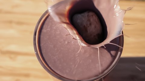 Chocolate milk pouring into a glass, splashing as it flows over, spilling on the table