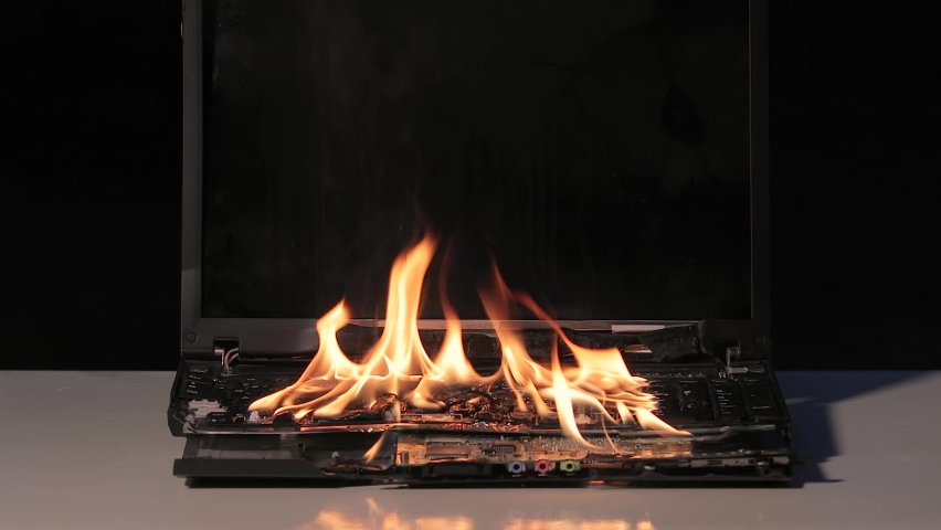 Laptop burning in flames on a desk, fire hazard. losing valuable data, 60 fps Royalty-Free Stock Footage #1062016582