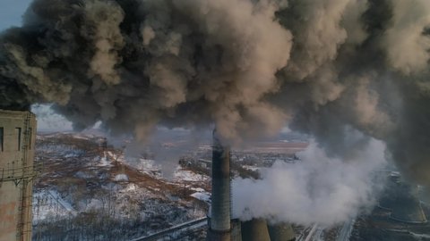 Drone around toxic enterprise chimneys tubing against the sky background release black smoke. Factory pollutes environment. Russia Primorsky Krai industrial countryside landscape. Winter day. Aerial Video Stok