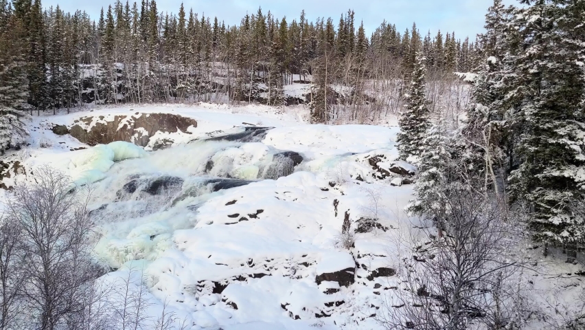 4K video of Cameron falls NWT half frozen waterfall in the early winter.