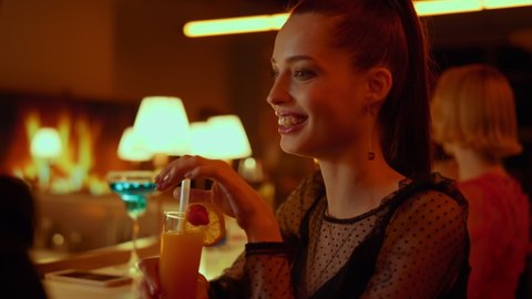 Closeup attractive woman flirting with young man in nightclub party. Smiling couple clinking glasses in bar at evening. Relaxed people resting and drinking cocktail in restaurant.
