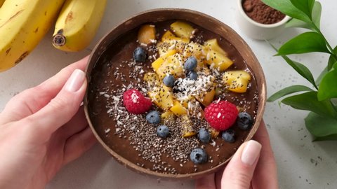 Vegan chocolate smoothie bowl with various toppings, mango raspberry blueberry coconut and chia seeds. Healthy food, clean eating, dieting concept