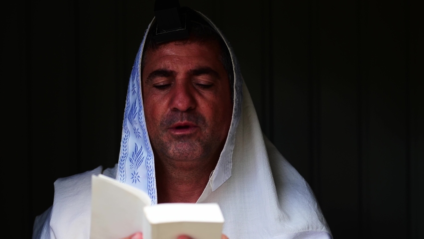 Adult Jewish man (male age 40-50) praying with with Tallit (prayer shawl) and Tefillin (phylacteries). Real people. Copy space  Royalty-Free Stock Footage #1062019909