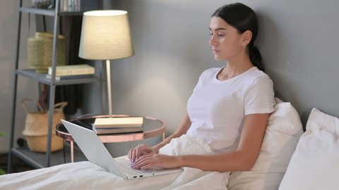 Latin Woman with Laptop having Back Pain in Bed 