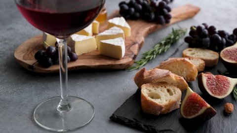 Cheese plate with fruits, camemebert cheese and glass of red wine. Italian appetizer starter plate