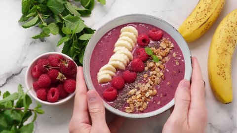 Pink smoothie bowl with raspberry, banana, granola and chia seeds. Top view. Healthy vegan smoothie bowl, trendy superfood