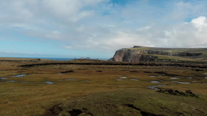 Girl Standing at the Edge of a Cliff Next to the Sea as a Drone Fly's By
