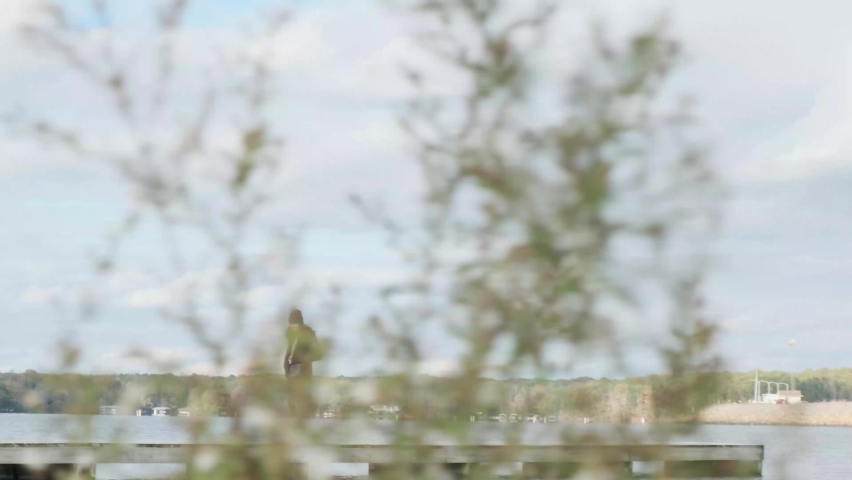 Pan through tall grass of woman walking across lake with a beautiful sky (60 fps slowed to 30 fps)