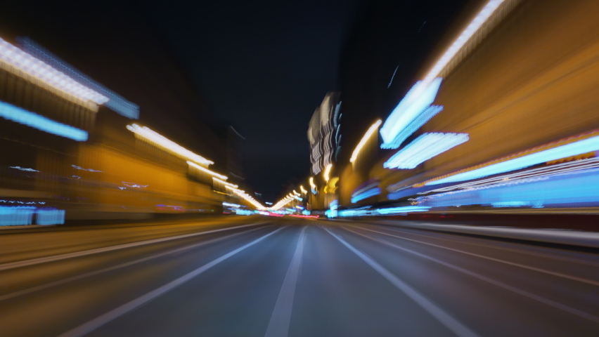 Amazing motion timelapse of a speedy night drive in a big city, front view from the car to the road. Glittering streets and building lights turning into beautiful light trails.  Royalty-Free Stock Footage #1062027631