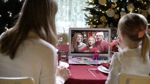 Two happy families with a children celebrating Christmas using a video call. Family greeting their relatives and friends on Christmas eve online. Social distancing, self isolation during quarantine