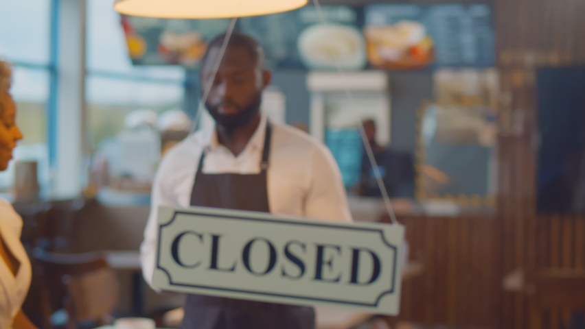 African cheerful small business owners smiling and turning open sign on cafe glass door. Happy successful afro-american couple of entrepreneurs opening new bistro restaurant Royalty-Free Stock Footage #1062029635