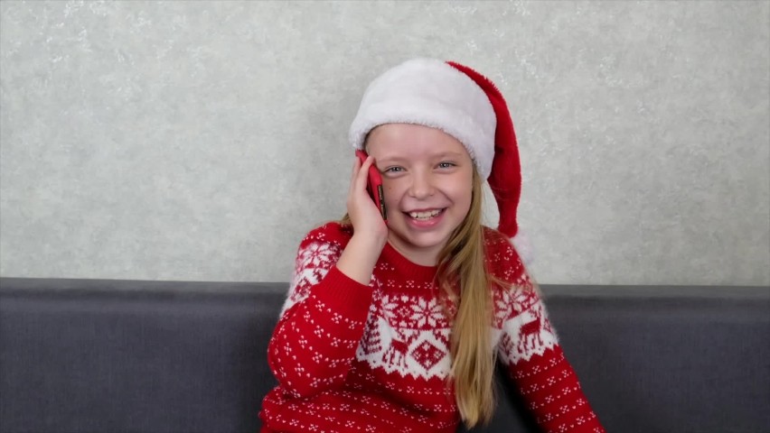 Small girl in Christmas hat talking to phone. Congratulations