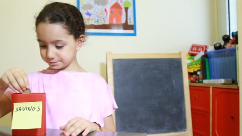 Kids saving money concept of girl insert coins to moneybox