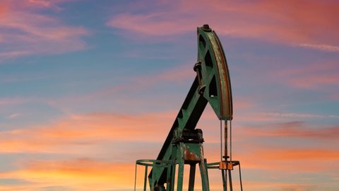 Pumping Oil Rig At Sunset. Pump Jack Extracting Crude Oil from a Oil Well. Fossil Fuel Energy. Oil Industry Equipment.