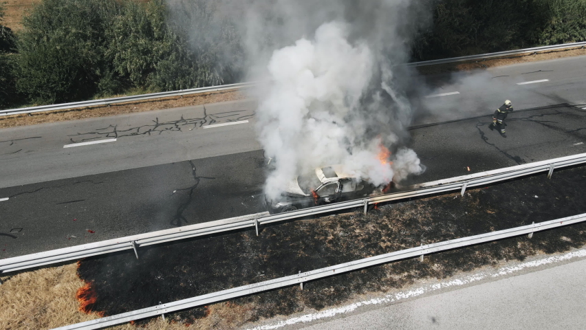 Firefighters extinguish burning car on highway following serious car accident on hot summer day aerial view. Fire truck came to the rescue. Flow of cars on track. Problem is on road. Traffic incident Royalty-Free Stock Footage #1062036376