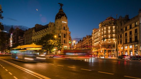 Madrid, Spain - October 12: Zoom out time lapse view of Madrid city centre, rush hour traffic on famous intersection showing landmark buildings on Gran Via street at dusk in the Spanish capital.