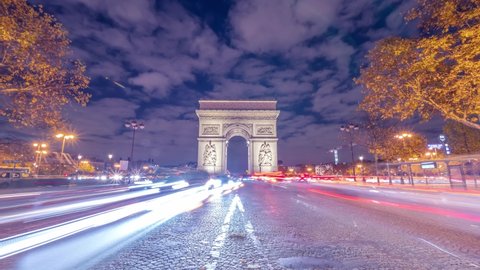 4K Timelapse of traffic at Arc de Triomph at night in an autumn winter day. This historical monument overlooks the avenue des champs élysées in the heart of Paris, French capital. 