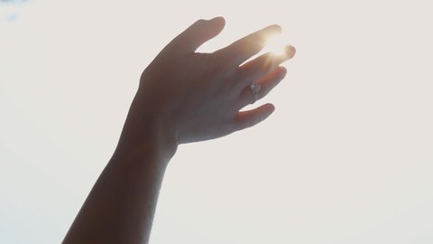 Girl's hand on the background of the sun. Ring on a woman's hand. The lights of a sun